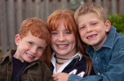 Casual outdoor portrait of three siblings huddled together with