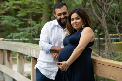 Outdoor portair of an expectant mother and father leaning on the